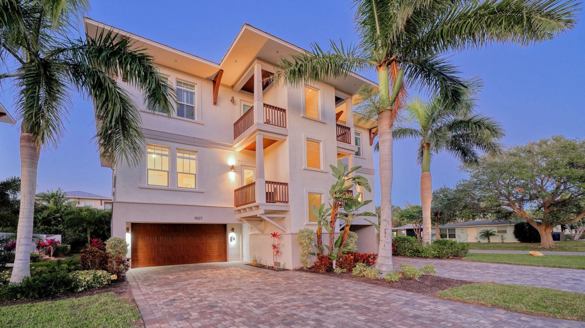 Your Siesta Key home base pairs tropical landscaping with multiple balconies and a two-car garage.