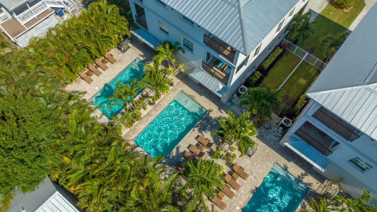 Your private sanctuary unfolds under twilight skies—two shimmering pools invite endless evening swims, surrounded by glowing palms and cozy lanai spaces.