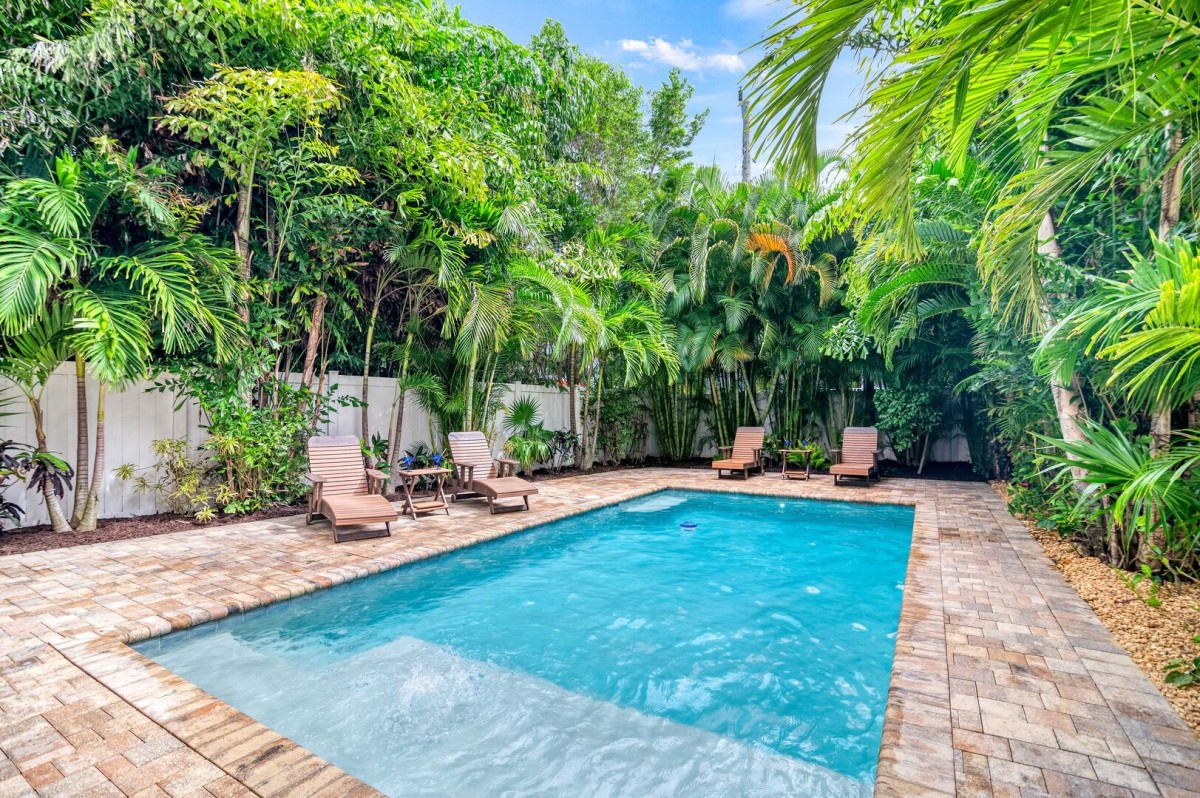 Poolside ambiance, complete with comfortable lounge chairs—sunlit water and lush palms create a tranquil escape.