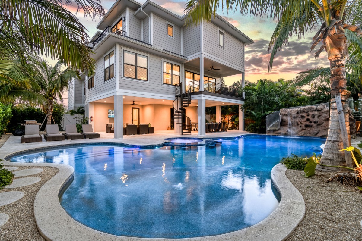 Backyard bliss! A private heated pool & spa. A rock waterfall with a pool slide. A row of tanning chaise lounges. Covered lanai for lounging and dining poolside.