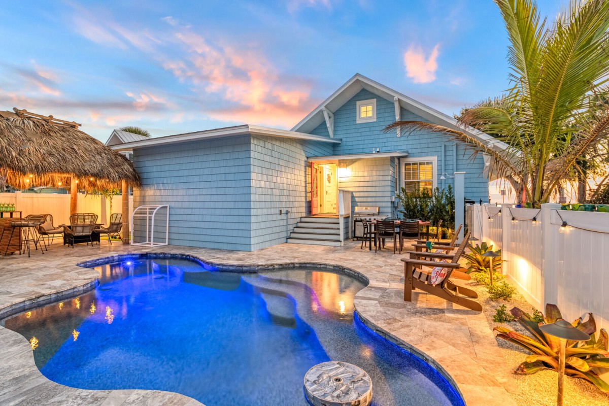 Private Heated Pool at twilight. At forefront of pool is an in-pool cocktail table with in pool seating around it.