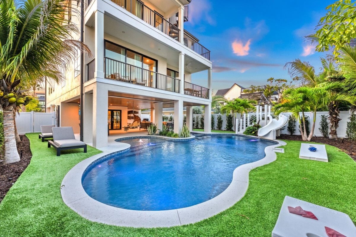 Easy outdoor living with pool, slide, and surrounding lounge space.
