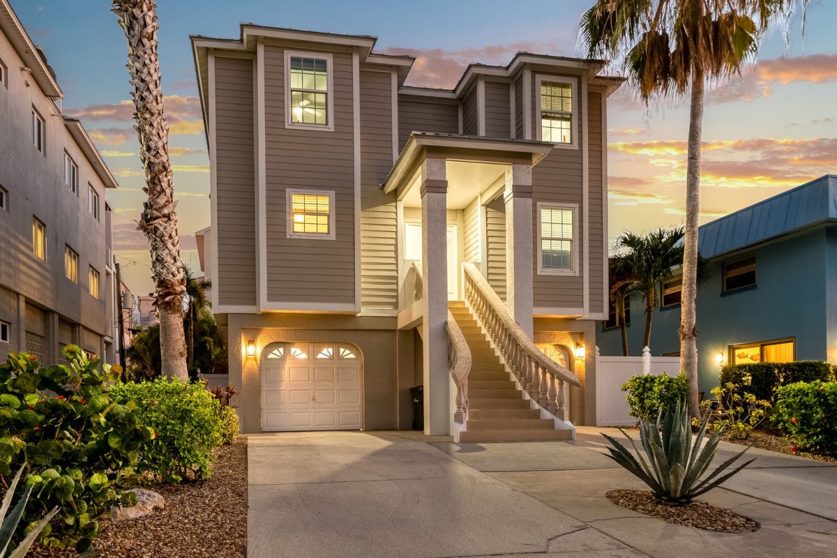 The home's front exterior glows under twilight, welcoming you with warm, inviting island lighting.
