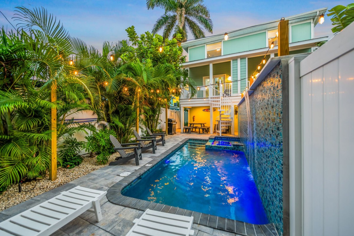 Tropical landscaping, a waterfall feature, and plenty of seating create a backyard designed for long, carefree afternoons.