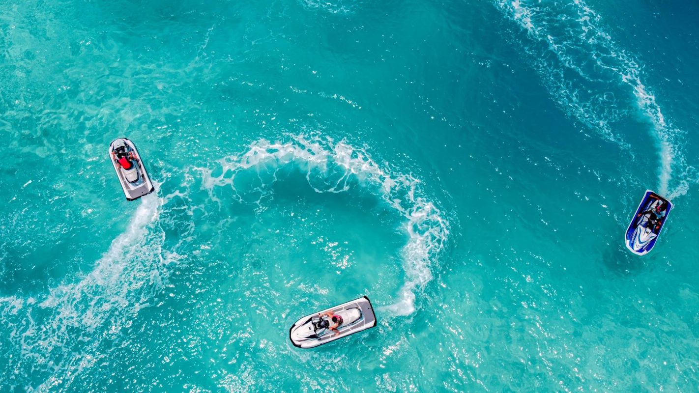 Three jet skis circle around one another in crystal blue water