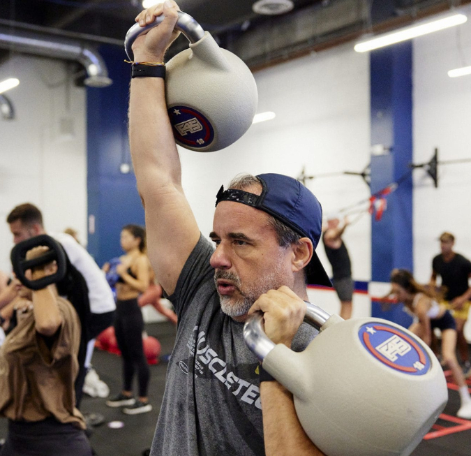 Athletic man lifting a heavy kettlebell weight during an intense indoor gym workout.