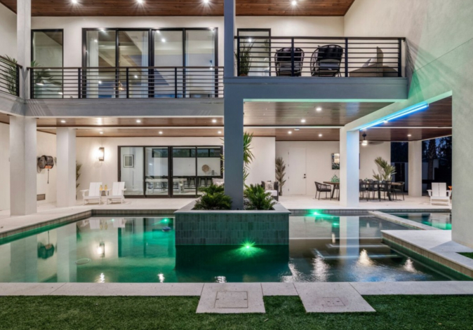 Modern multi-story luxury villa featuring an illuminated courtyard swimming pool at night.