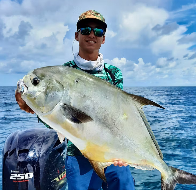 Fisherman holding up a massive silver fish caught on a deep-sea charter boat trip.