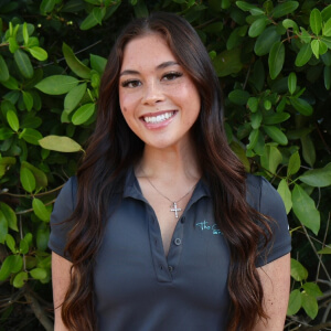 Smiling female team member with long hair posing outdoors.