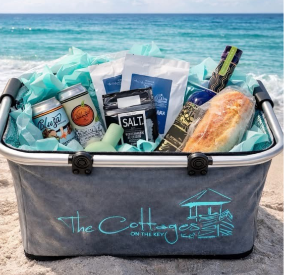 Gift basket filled with local treats, wine, and a fresh baguette in a turquoise tote.