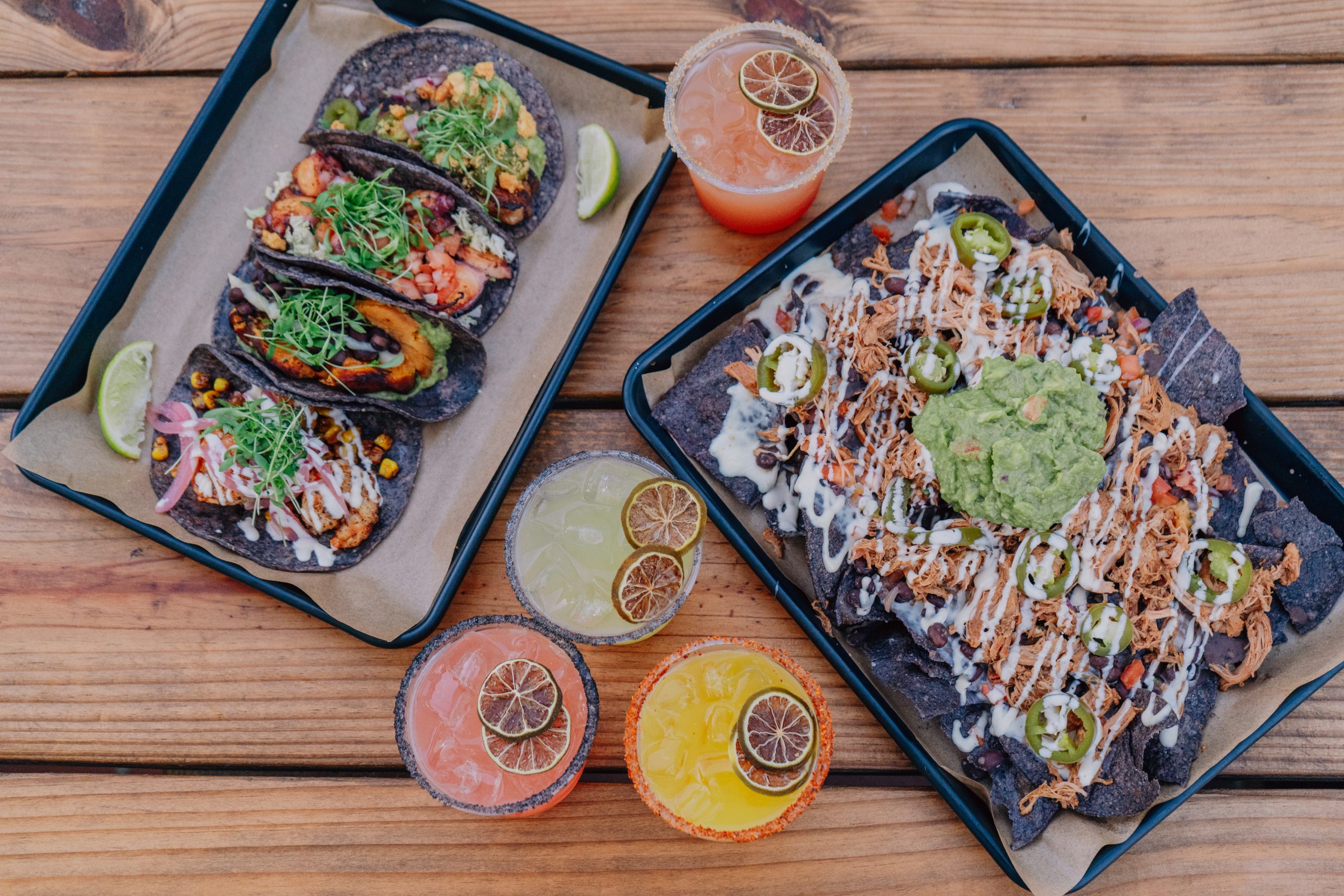 Flat lay of multiple Mexican dishes and refreshing drinks arranged on plates.