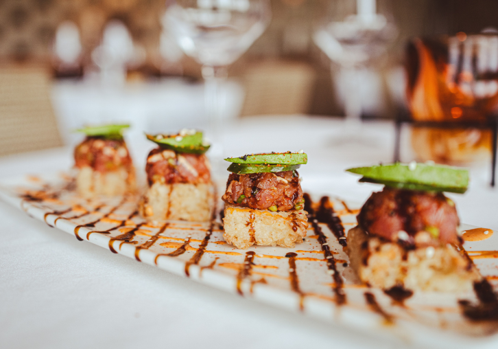 Gourmet bacon-wrapped appetizers lined up on a rectangular serving platter.