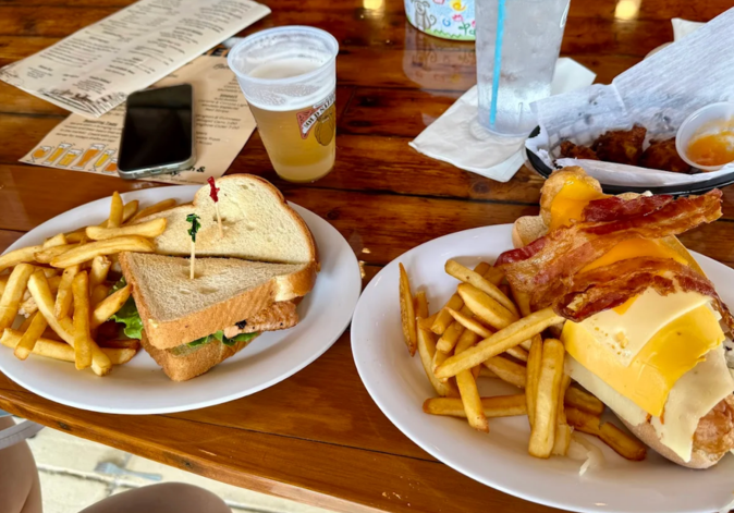 Two plates featuring breakfast sandwiches and French fries served outdoors.