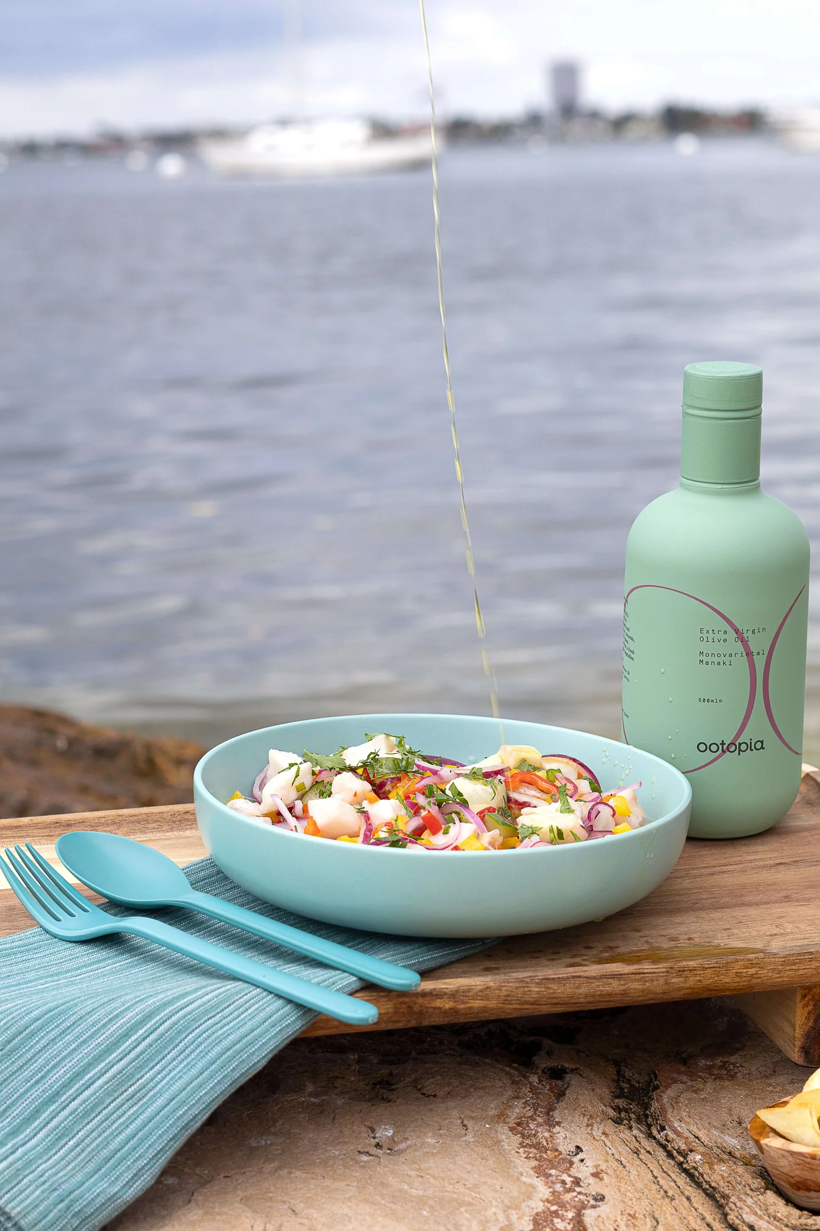 ootopia olive oil bottle next to bowl of ceviche being dressed with olive oil